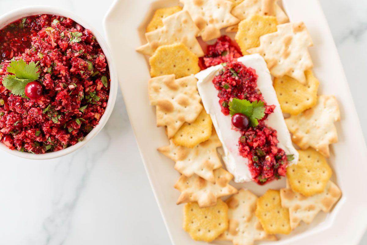 Cranberry-Salsa 2 Ein Teller voller Cracker, die Cranberry-Salsa auf einem Block Frischkäse umgeben