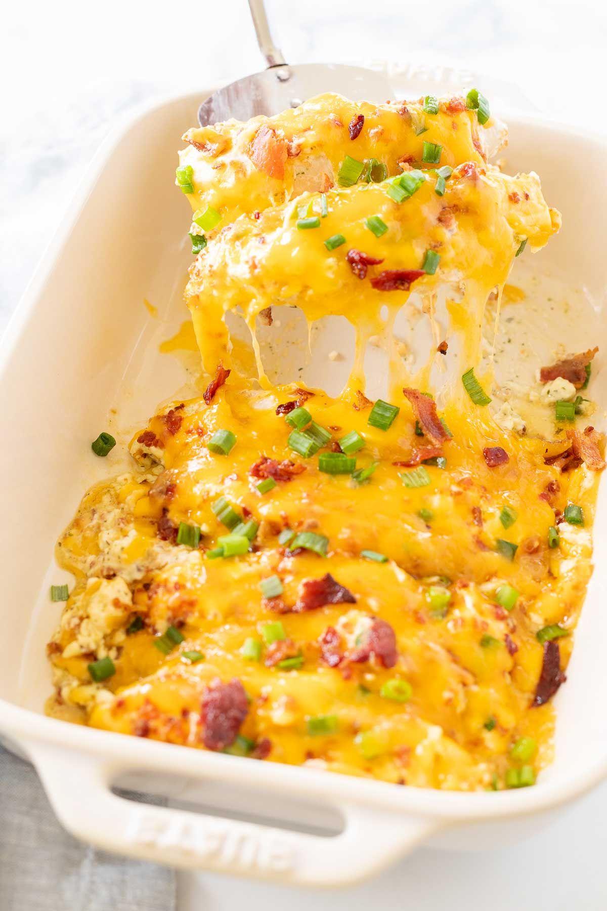 Ein Teller mit cremigem 'Crack Chicken' mit Ranch-Würze, Käse und Speck, garniert mit frischen Frühlingszwiebeln.