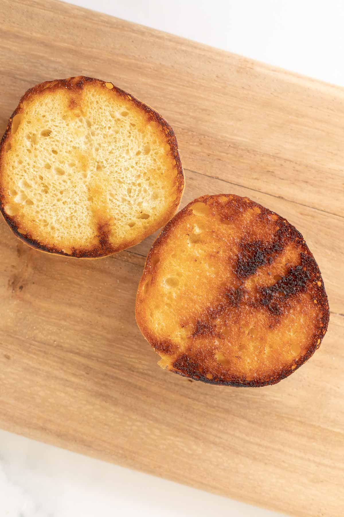 Warum man Burgerbrötchen rösten sollte 2 Ein getoastetes Burger Bun auf einem Holzschneidebrett