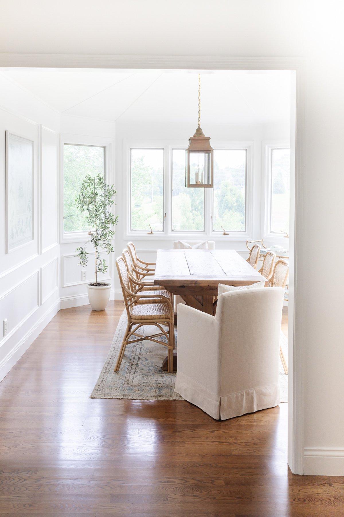 Holzboden-Lasurfarben 2 Ein elegantes Esszimmer mit einem weißen Esstisch und passenden Stühlen, das von einem warmen, harmonisch gebeizten Hartholzboden geerdet wird.