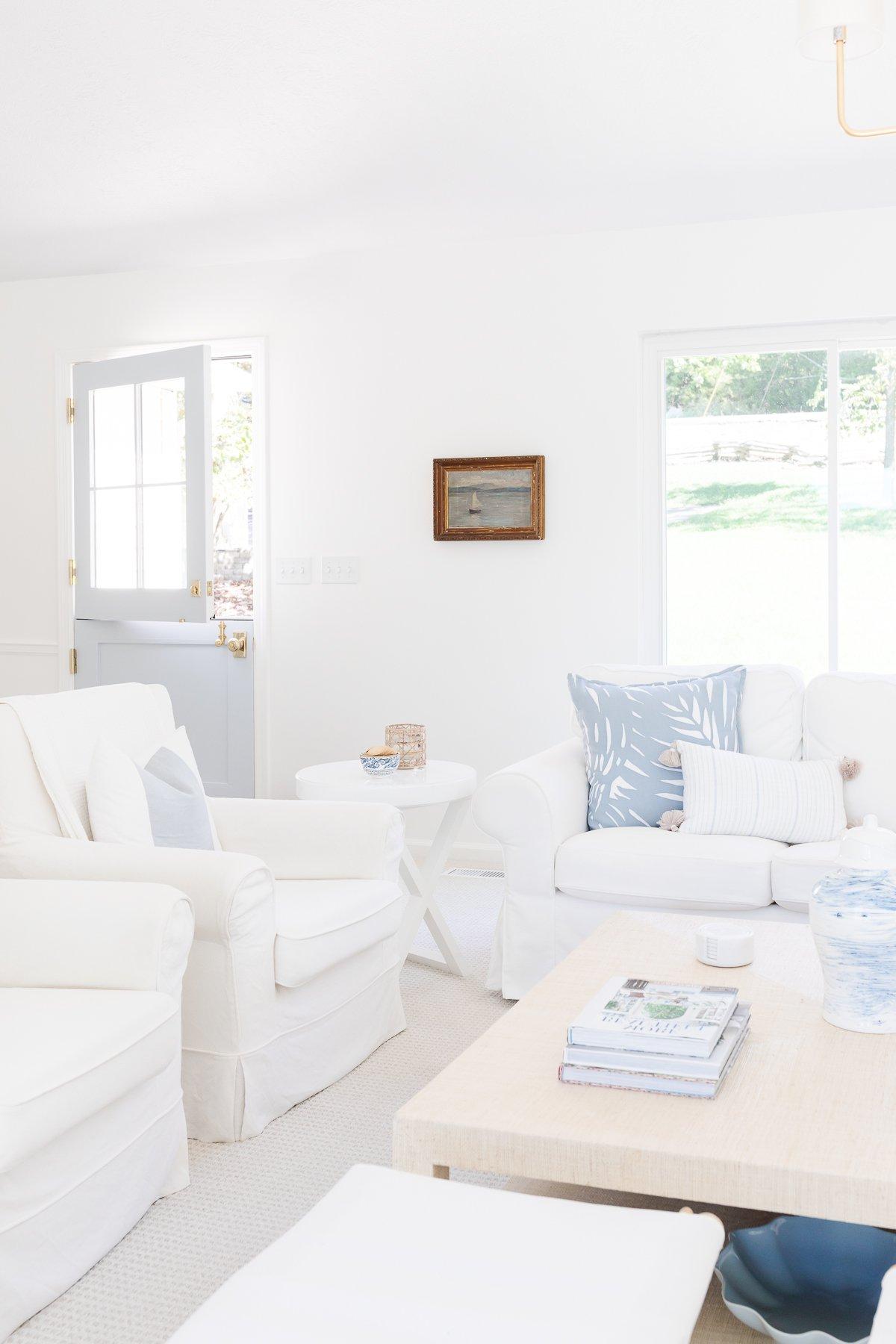 Benjamin Moore Einfach Weiß 2 Ein weißes Wohnzimmer mit blauen Akzenten, Wände gestrichen in Benjamin Moore Simply White.