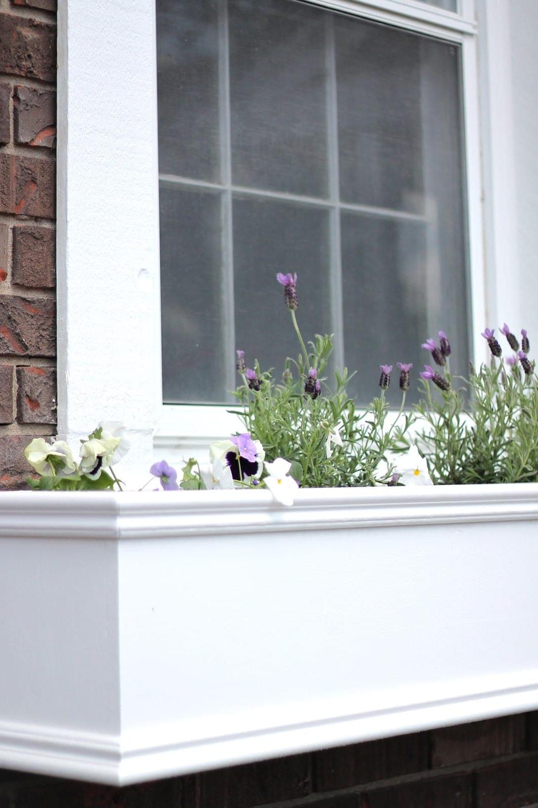 Ein weißer DIY-Fensterkasten gefüllt mit Frühlingsblumen.