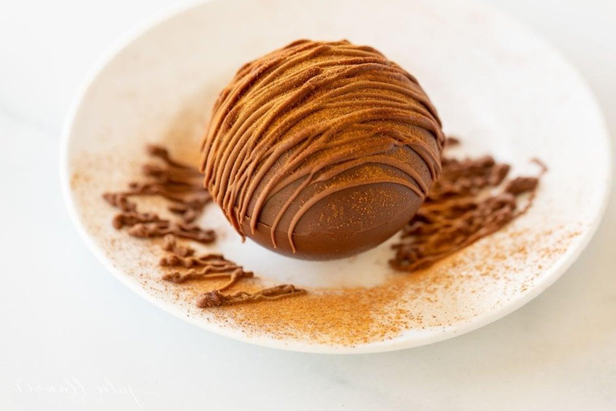 Mexikanische Heiße Schokoladenbomben 2 Ein mexikanischer Trinkschokolade Bombe auf einem weißen Teller, appetitlich angerichtet.