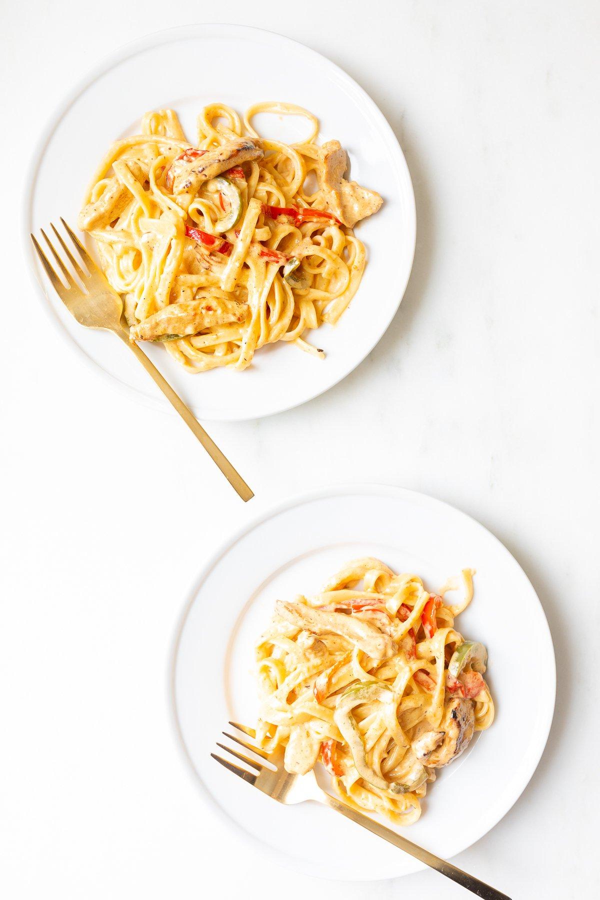 Wie man Nudeln aufwärmt 2 Zwei weiße Teller mit Pasta und goldenen Gabeln.