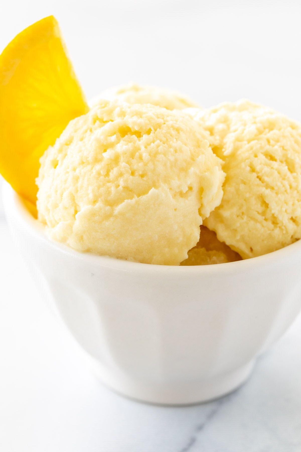 Orangen-Sorbet 2 Orangen-Sherbet, garniert mit einer Orangenscheibe in einer weißen Schale