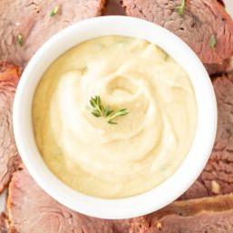 Eine weiße Schale voller Dijon-Sauce, umgeben von Rinderfilet.