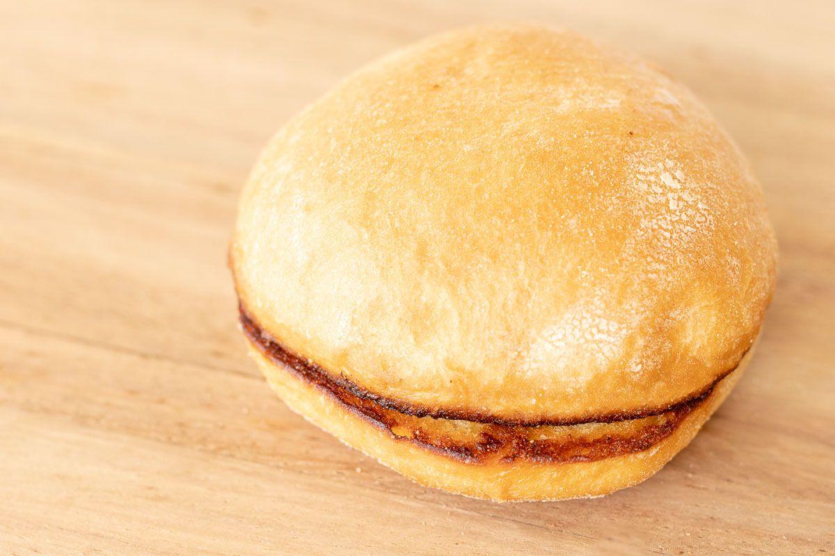 Warum man Burgerbrötchen rösten sollte 11 Ein getoastetes Burger Bun auf einem Holzschneidebrett