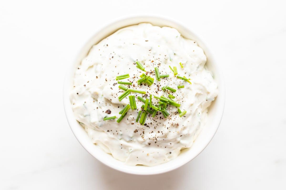 Ein cremiger Blauschimmelkäse-Dip in einer weißen Schale, makellos präsentiert.
