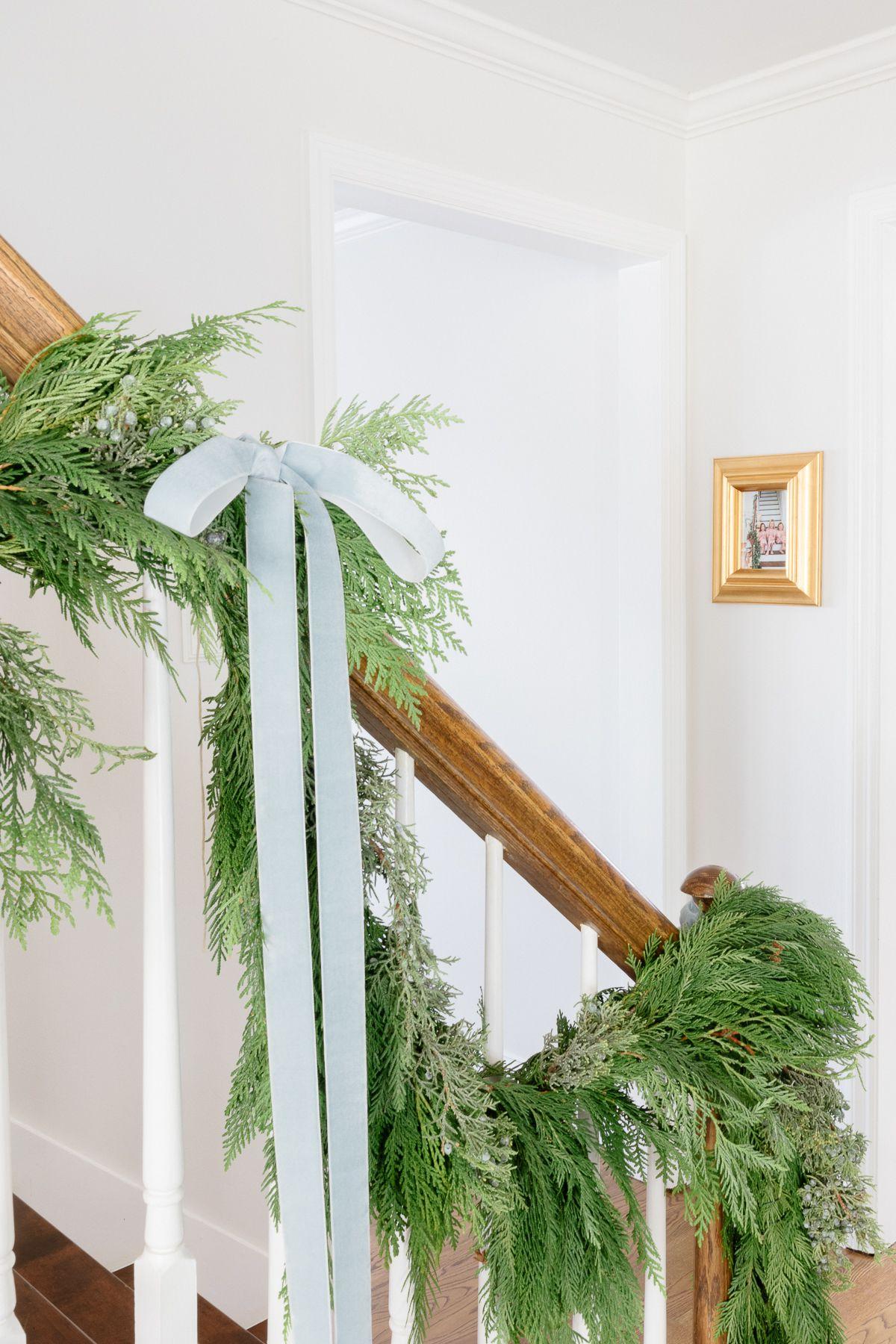 Frische grüne Girlande an einer Holztreppe als minimalistische Weihnachtsdekorationsidee.