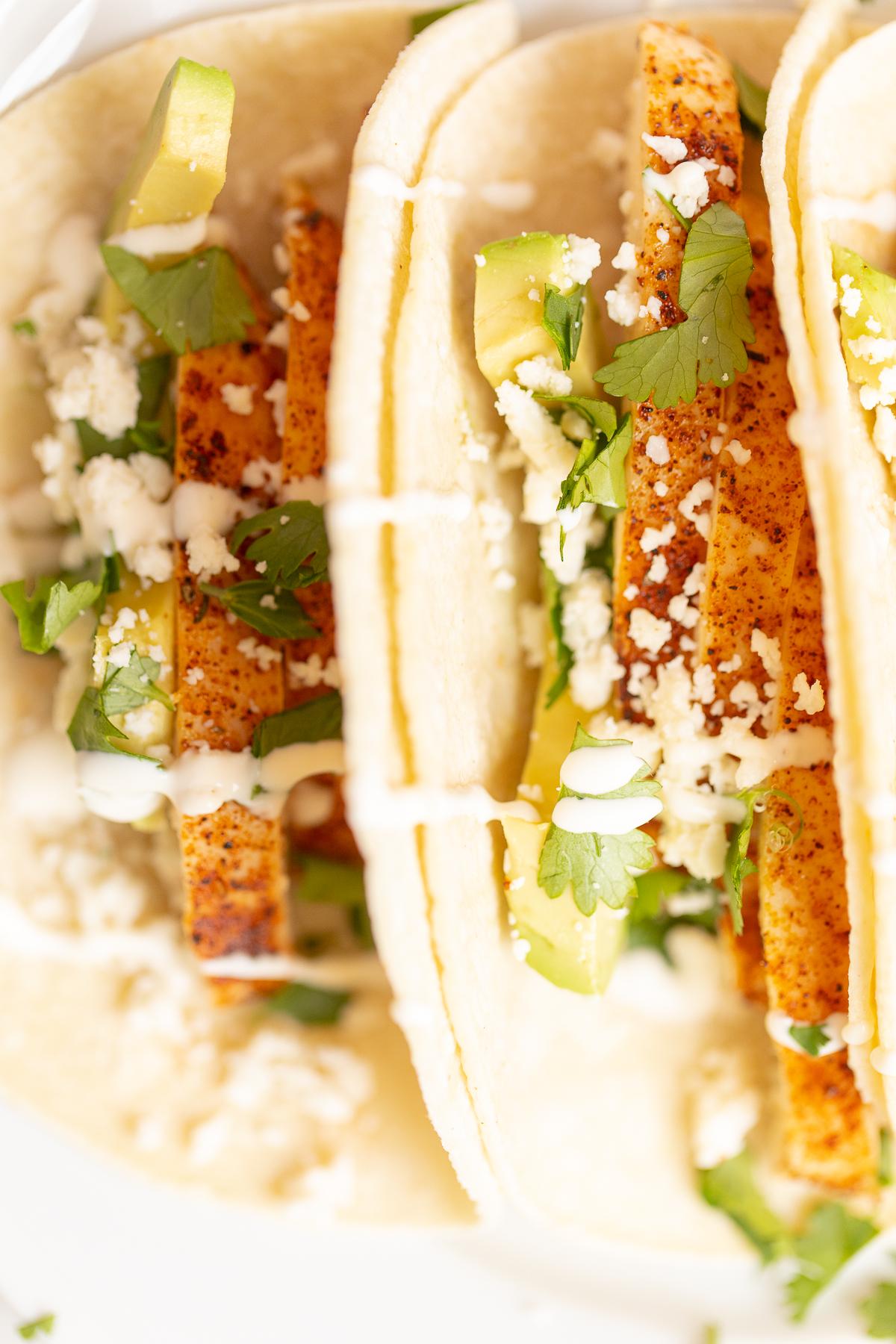 Weiche Hähnchen-Tacos 11 Hähnchen-Tacos in Mais-Tortillas auf einer weißen Oberfläche.