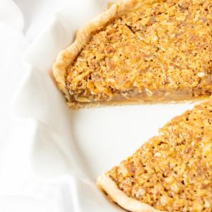 Ein dekadenter Karamell-Pekannusskuchen, aus dem ein Stück herausgeschnitten wurde, was seine verlockende Textur zeigt.