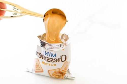 Erdnussbutter wird in eine offene Packung Mini-Chessmen-Butterkekse geschöpft.