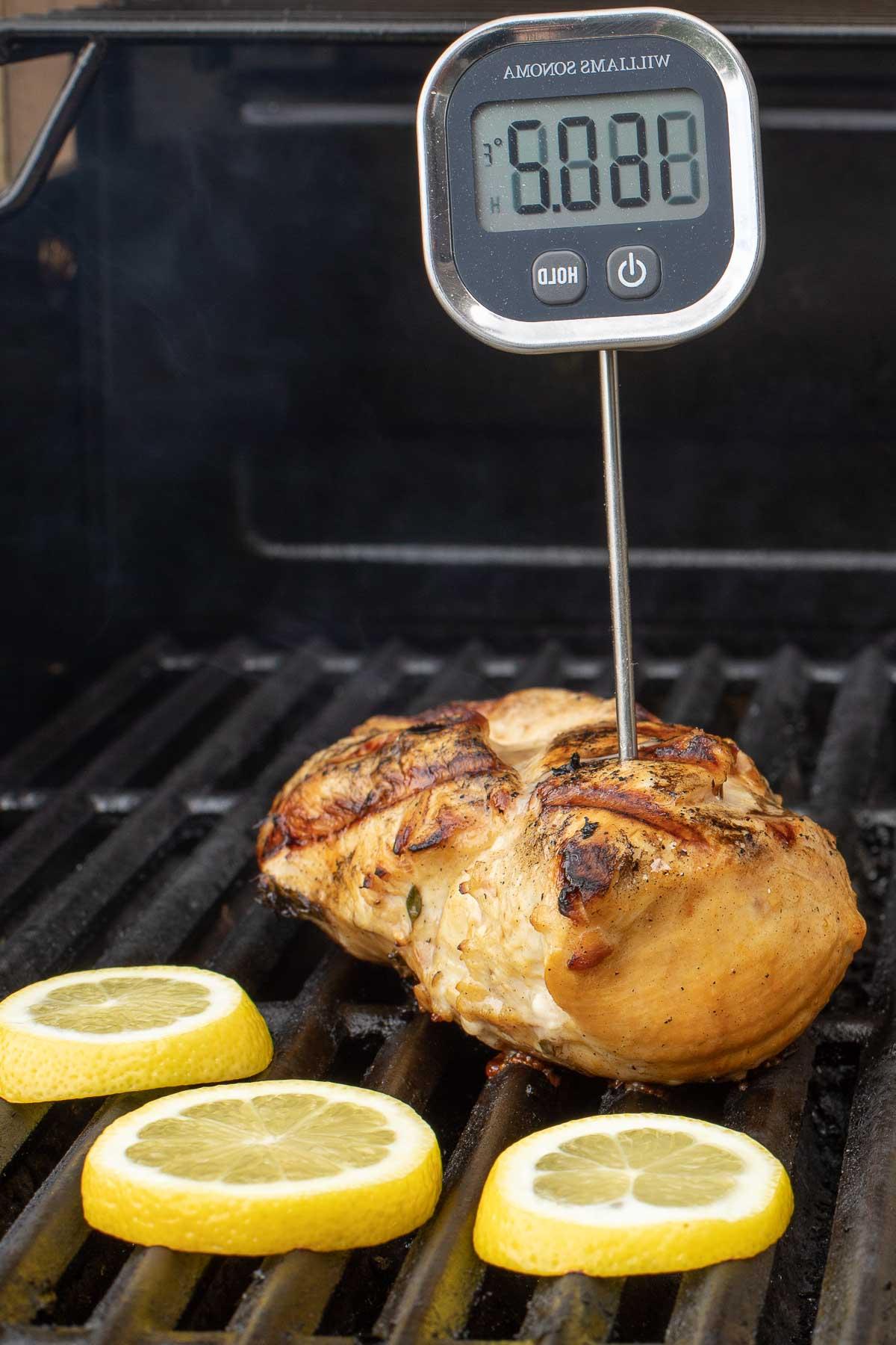 Gegrilltes griechisches Hähnchen und Zitronenscheiben auf einem Gasgrill.