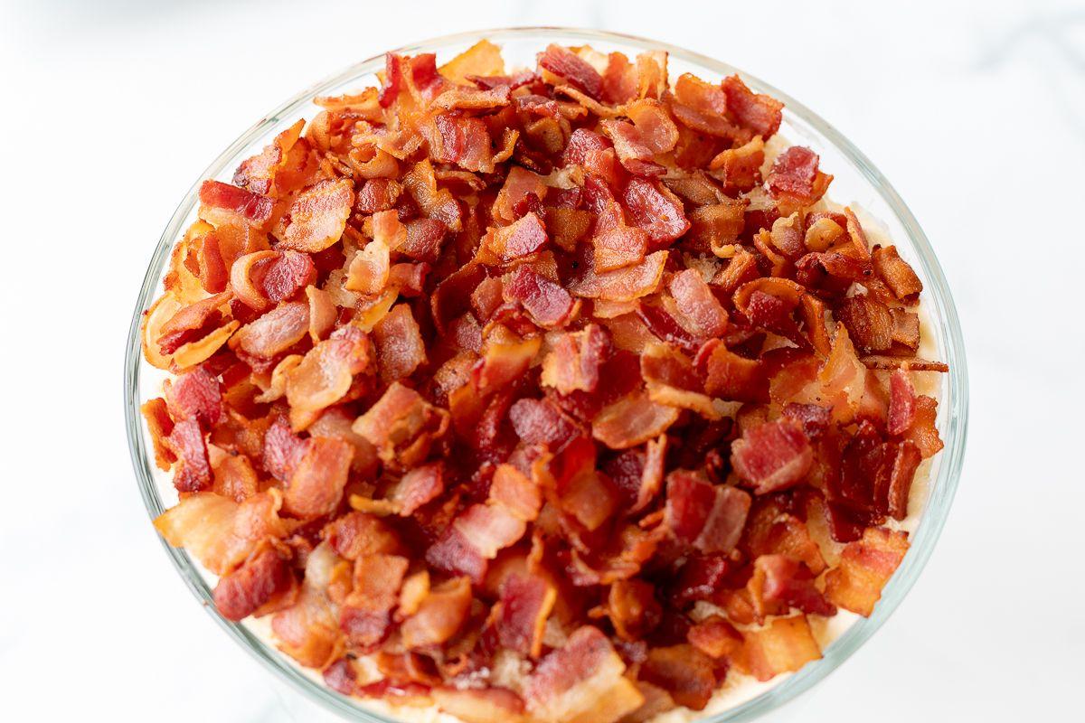 Eine durchsichtige Glasschale mit Salat, belegt mit gehacktem Speck