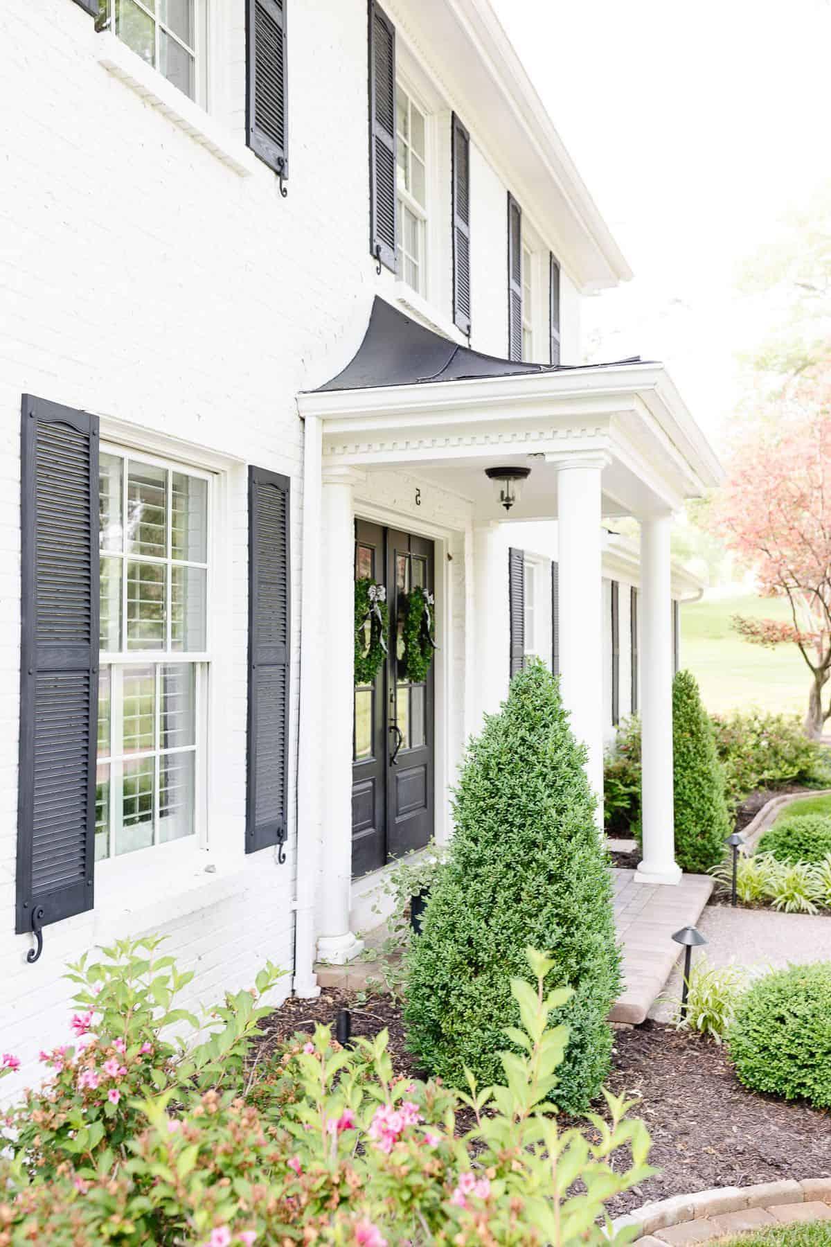 Benjamin Moore Einfach Weiß 13 Simply White Benjamin Moore Außenansicht eines Kolonialhauses mit schwarzen Fensterläden.