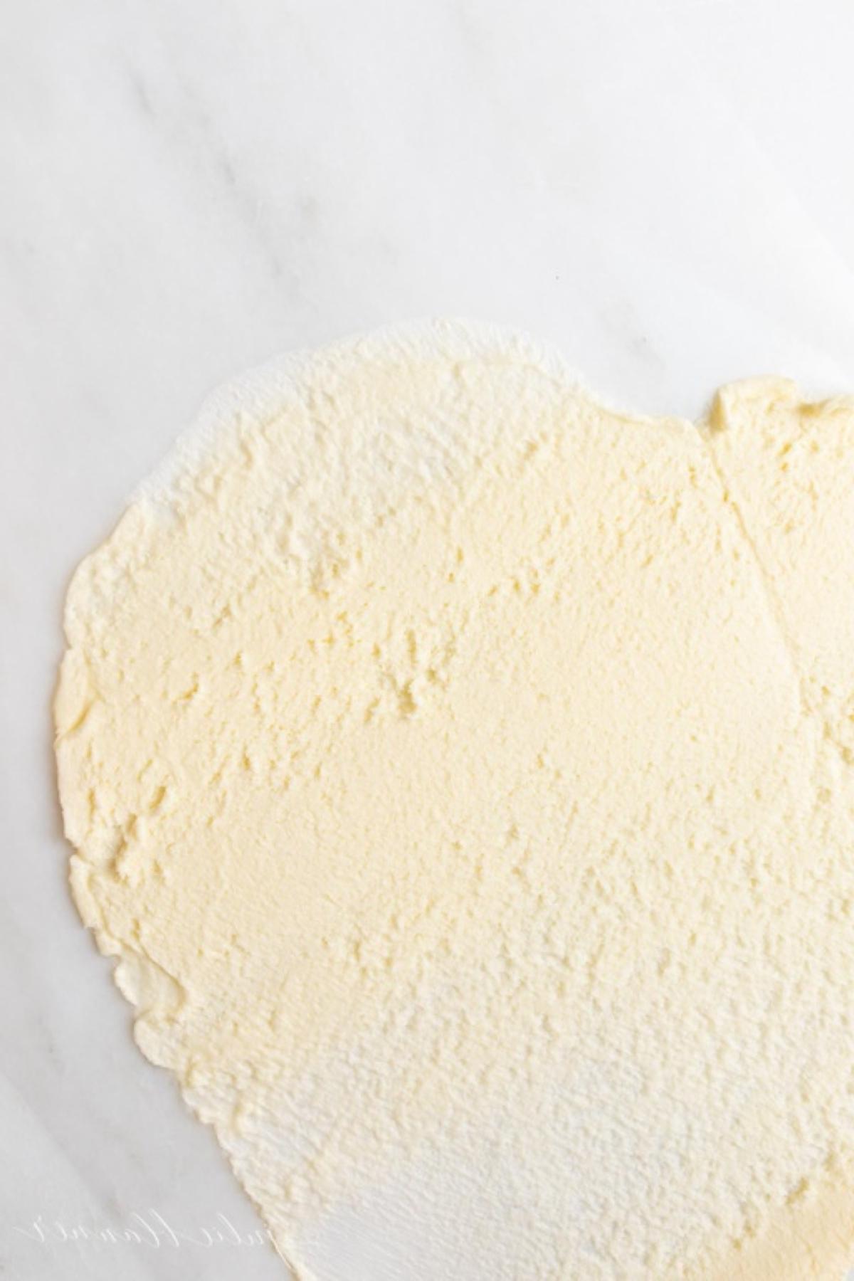 Ein Stück Butter, das mit einem Nudelholz in einem Tutorial für weiche Butter flachgedrückt wurde.