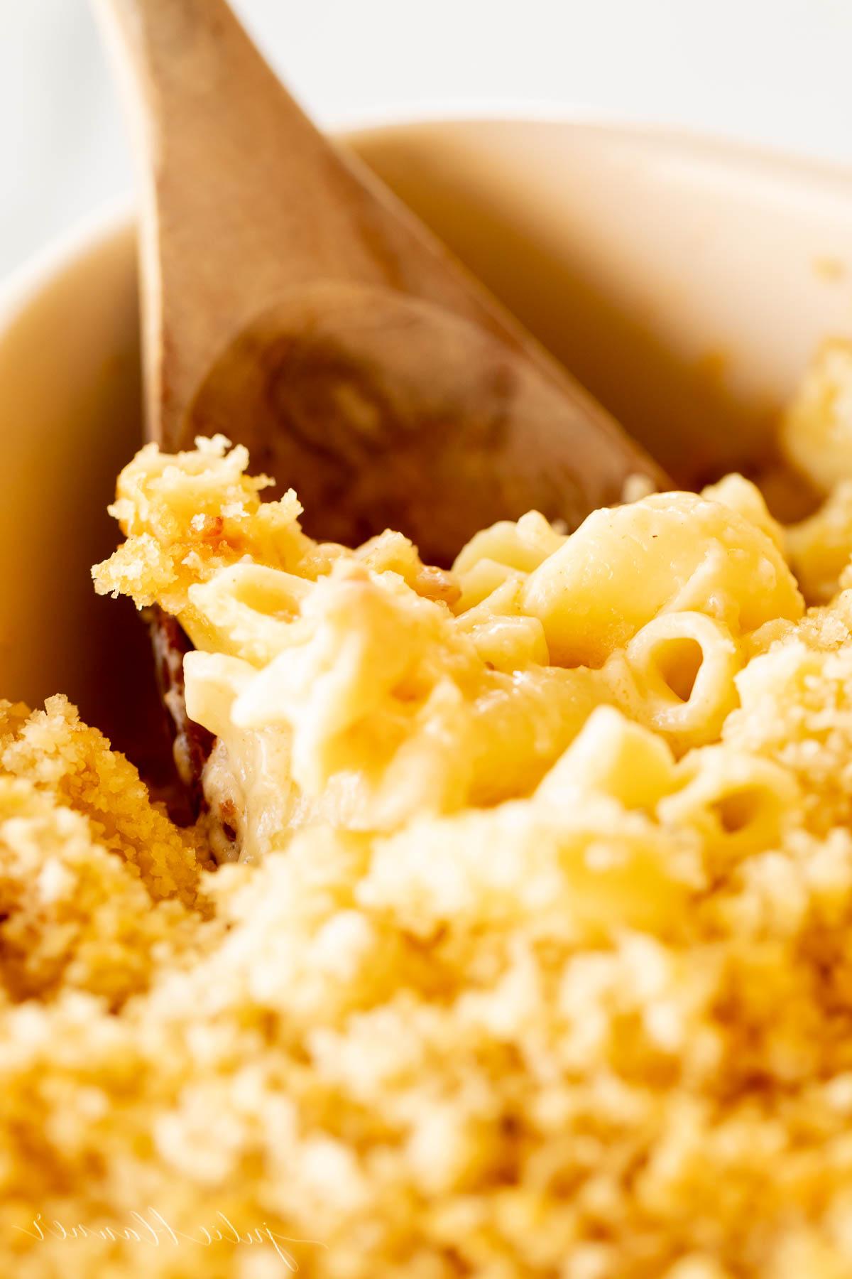 Speck Mac and Cheese in einer weißen Auflaufform, mit einem Holzlöffel in der Ecke.