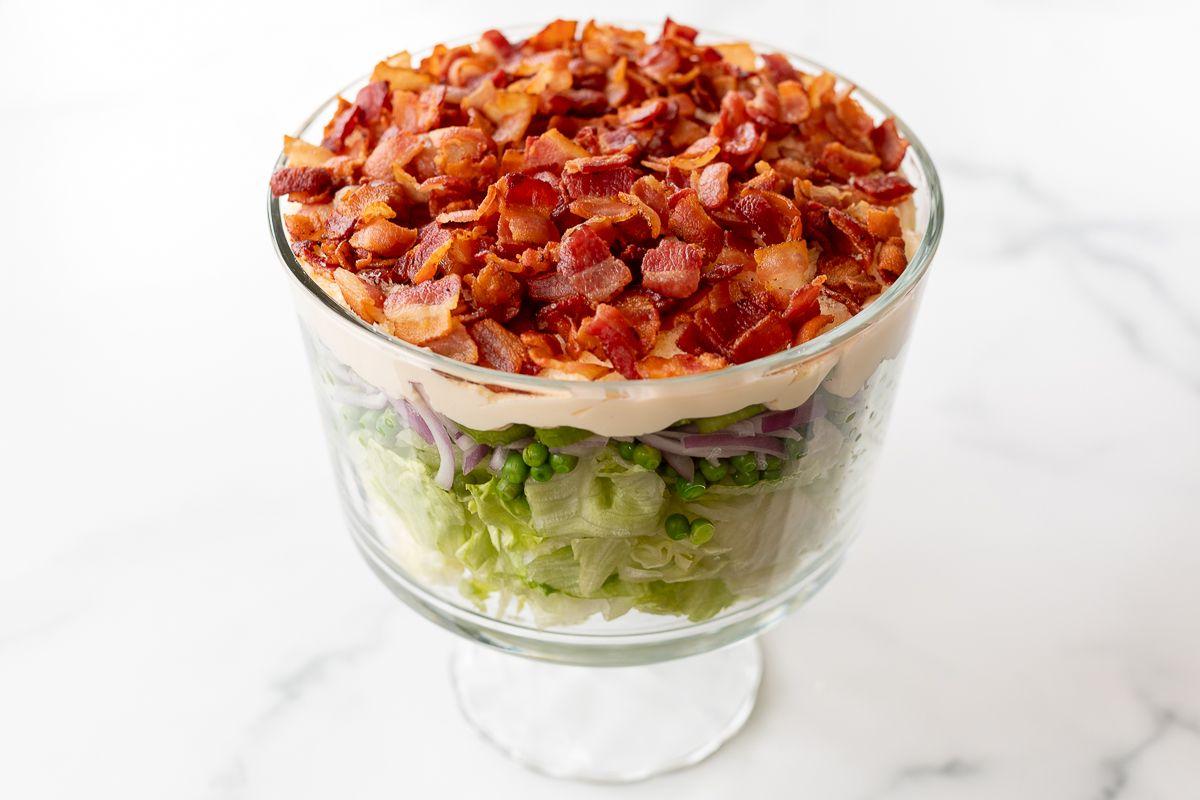 Siebenschichtsalat 14 Sieben-Schicht-Salat mit Speck belegt auf einer Marmorarbeitsplatte