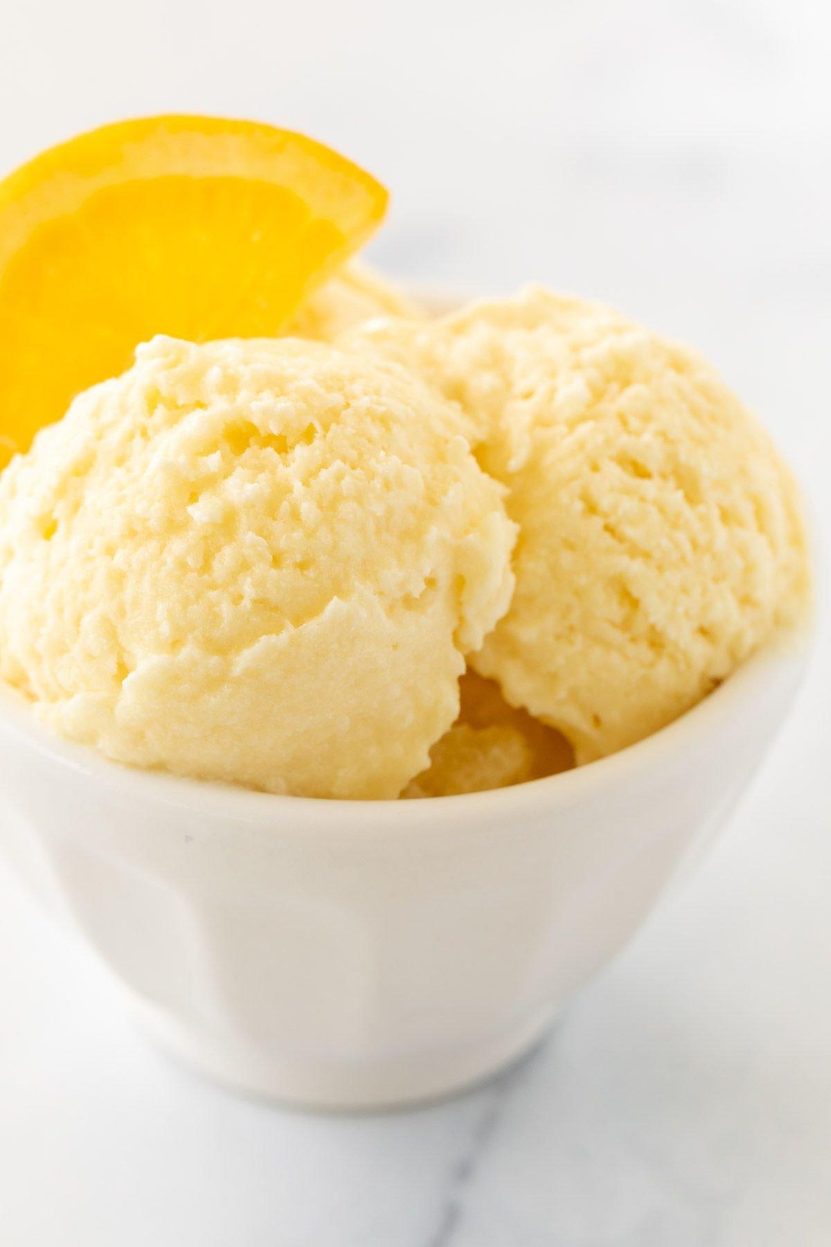 Orangen-Sorbet 15 Orangen-Sherbet, elegant garniert mit einer Orangenscheibe in einer weißen Schale