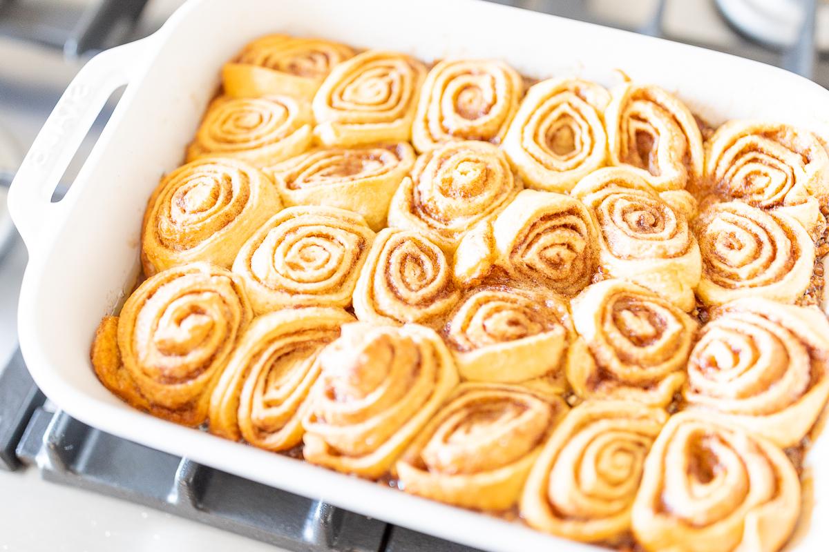 Karamell-Pekannuss-Rollen 15 Pekannussbrötchen in einer Auflaufform auf einem Herd.