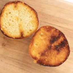 Warum man Burgerbrötchen rösten sollte 15 Ein getoastetes Burger Bun auf einem Holzschneidebrett