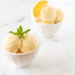 Orangen-Sorbet 16 Zwei kleine weiße Schalen voll mit Orangen-Sherbet auf einer Marmoroberfläche