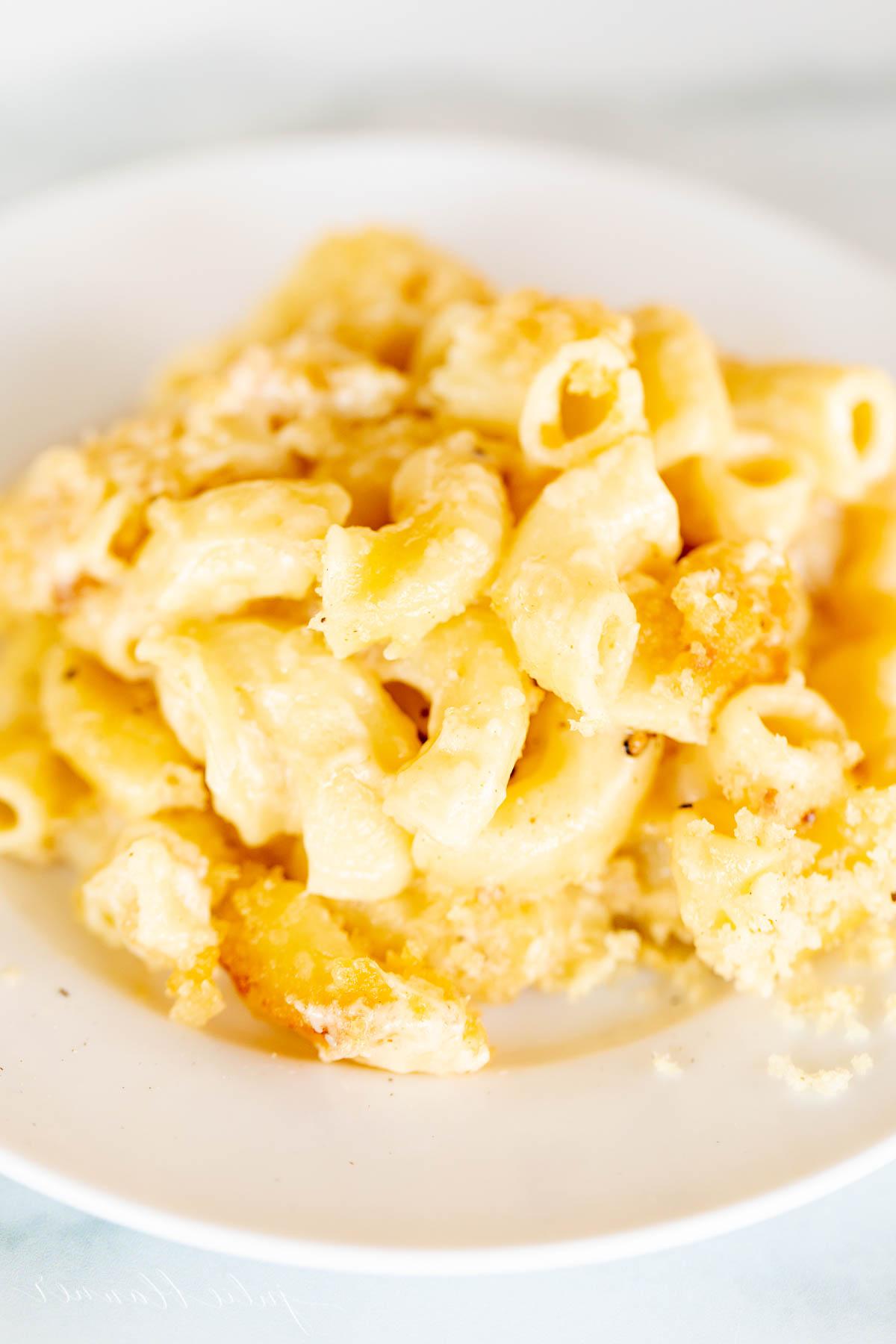 Cremige Makkaroni und Käse mit knusprigem Speck belegt, auf einem weißen Teller serviert.