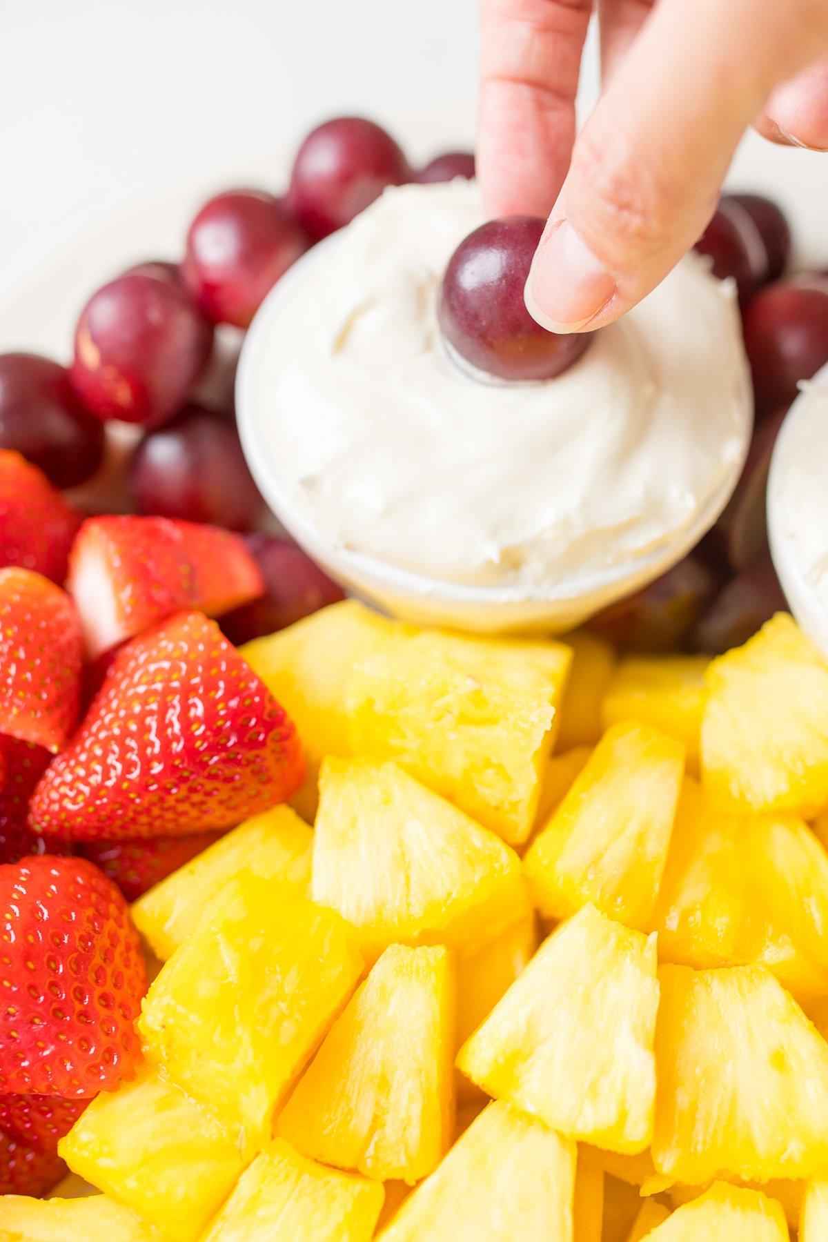 Muttertags-Brunch-Ideen 16 Eine weiße Keramikplatte voller geschnittenem Obst und eine kleine weiße Schale mit Frischkäse-Marshmallow-Frucht-Dip.
