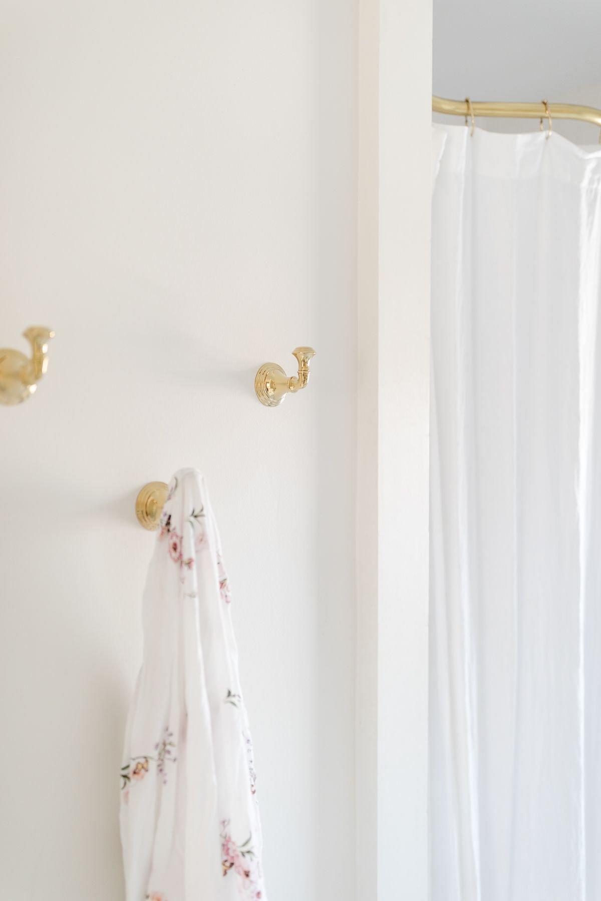 So erstellen Sie ein Spa-Bad zu Hause 16 Goldene Bademantelhaken an der Wand eines weißen Spa-Bades, die Eleganz und Funktionalität verbinden.