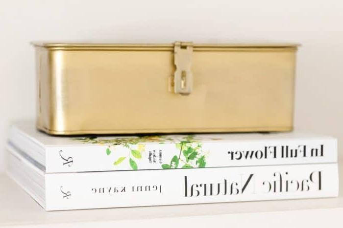 Weiße Bücher mit einer goldenen Box oben für Regal-Styling.
