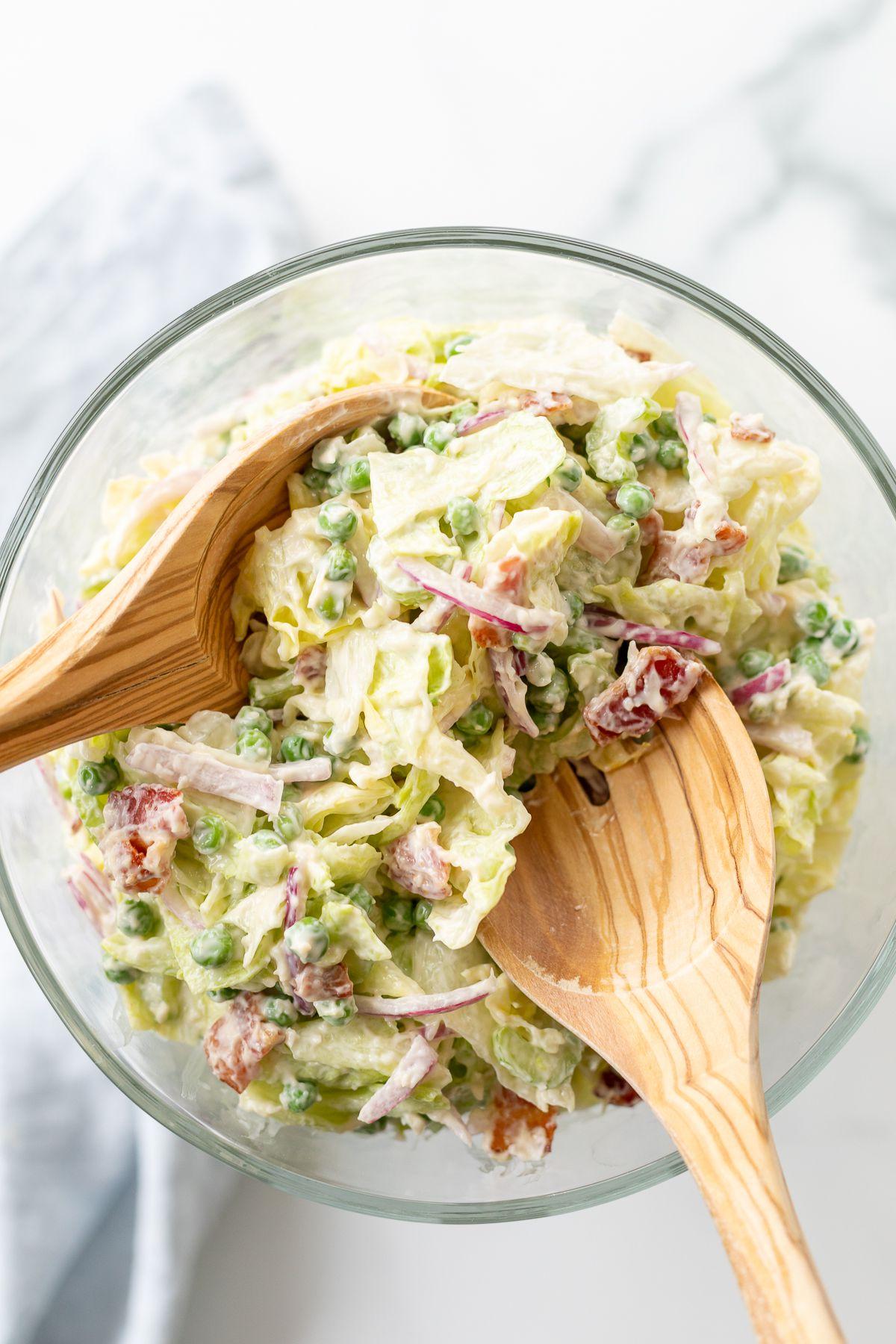 Siebenschichtsalat 17 Ein Sieben-Schicht-Salat, in einer Glasschale angerichtet, mit Holzlöffeln daneben