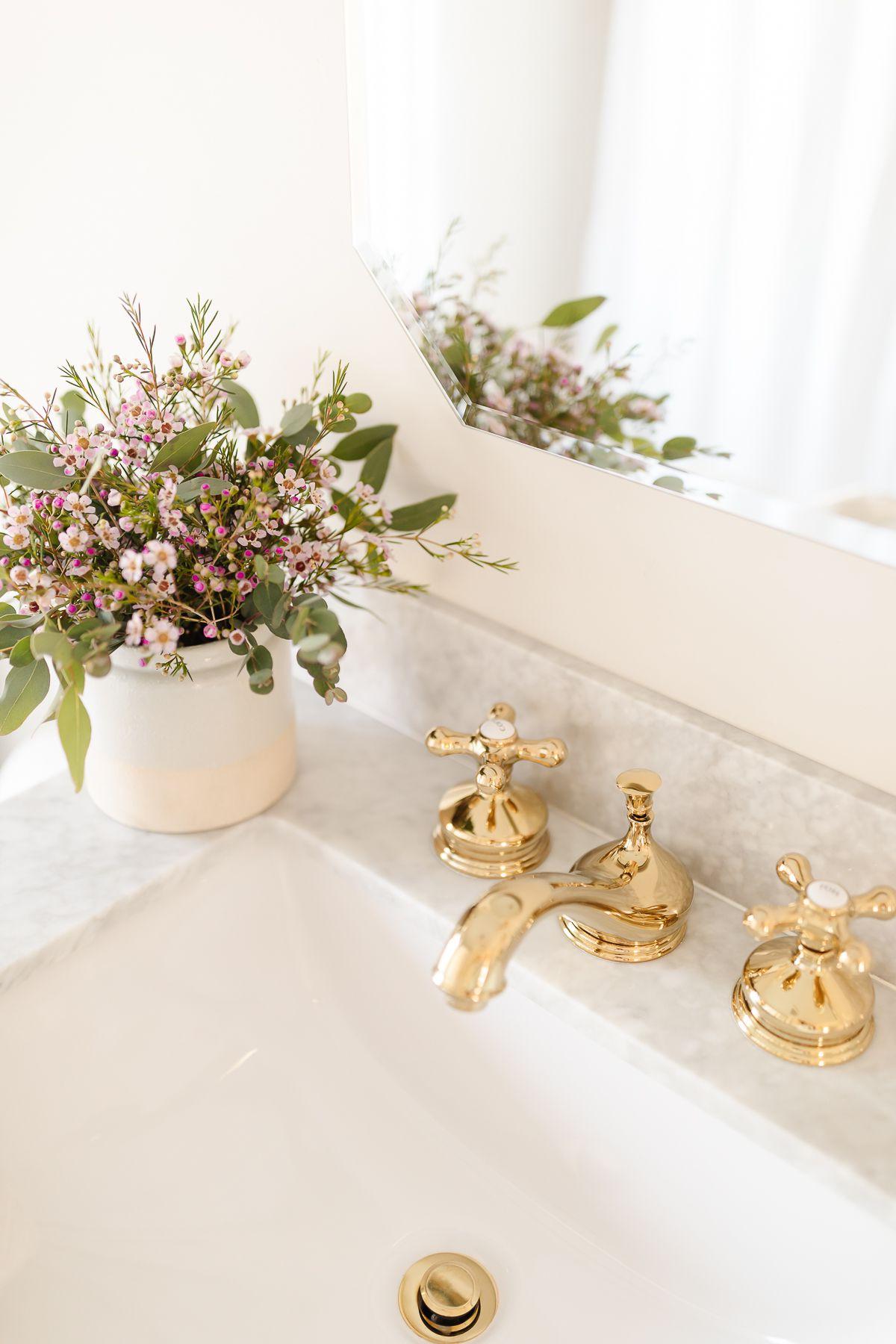 So erstellen Sie ein Spa-Bad zu Hause 17 Ein Messing-Wasserhahn auf einer Marmor-Arbeitsplatte in einem Badezimmer, der das Auge durch seine Eleganz anzieht.