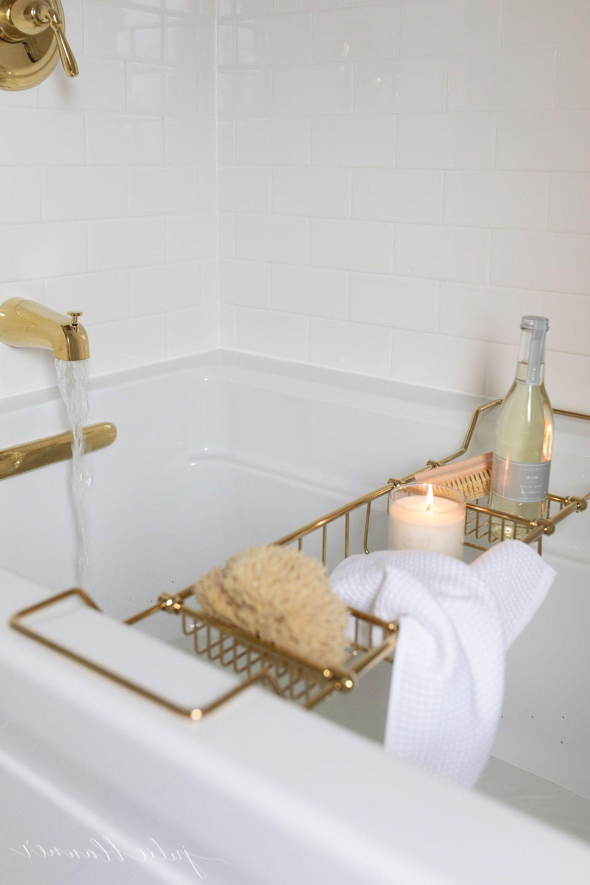 So erstellen Sie ein Spa-Bad zu Hause 18 Ein Spa-Bad mit einem goldenen Badewannentablett, gefüllt mit Badeartikeln, das eine einladende Atmosphäre schafft.
