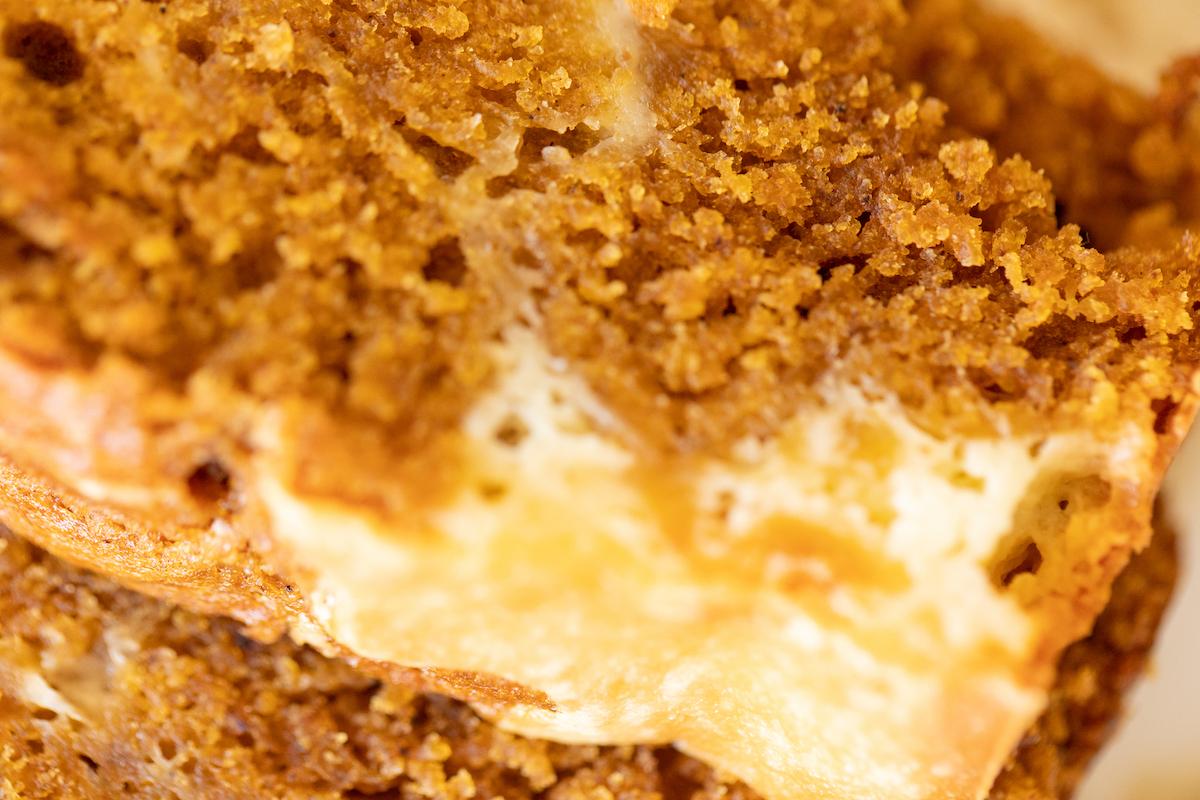 Ein weiteres appetitliches Bild eines ganzen Laibs Kürbis-Käsekuchen-Brot auf einer weißen Platte, das die reichhaltige Farbe und die Textur betont.