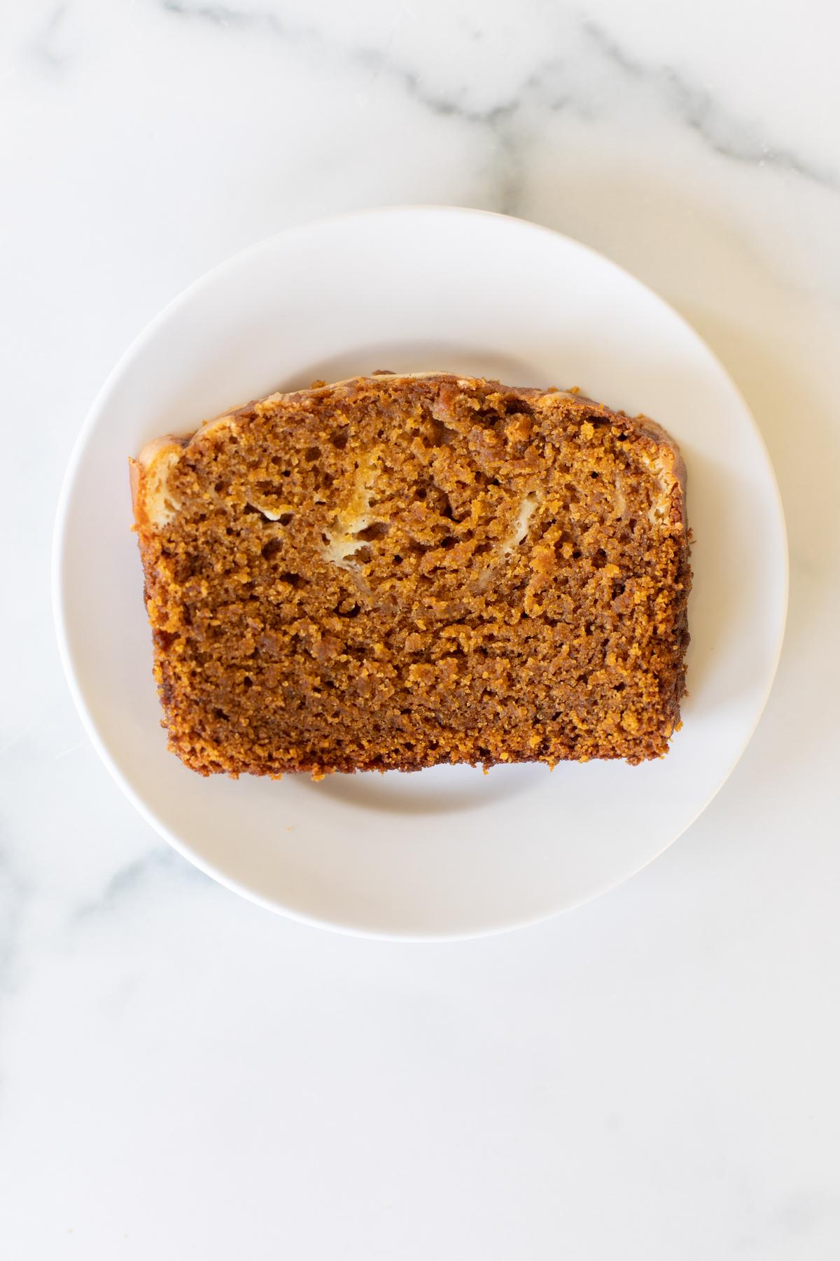 Eine dicke Scheibe Kürbis-Käsekuchen-Brot auf einem weißen Teller, die Füllung ist gut sichtbar und das Brot ist perfekt gebacken.