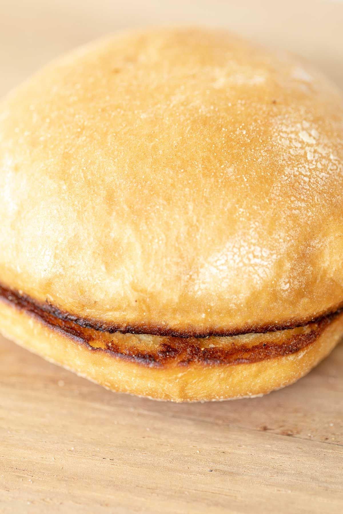 Warum man Burgerbrötchen rösten sollte 3 Ein getoastetes Burger Bun auf einem Holzschneidebrett