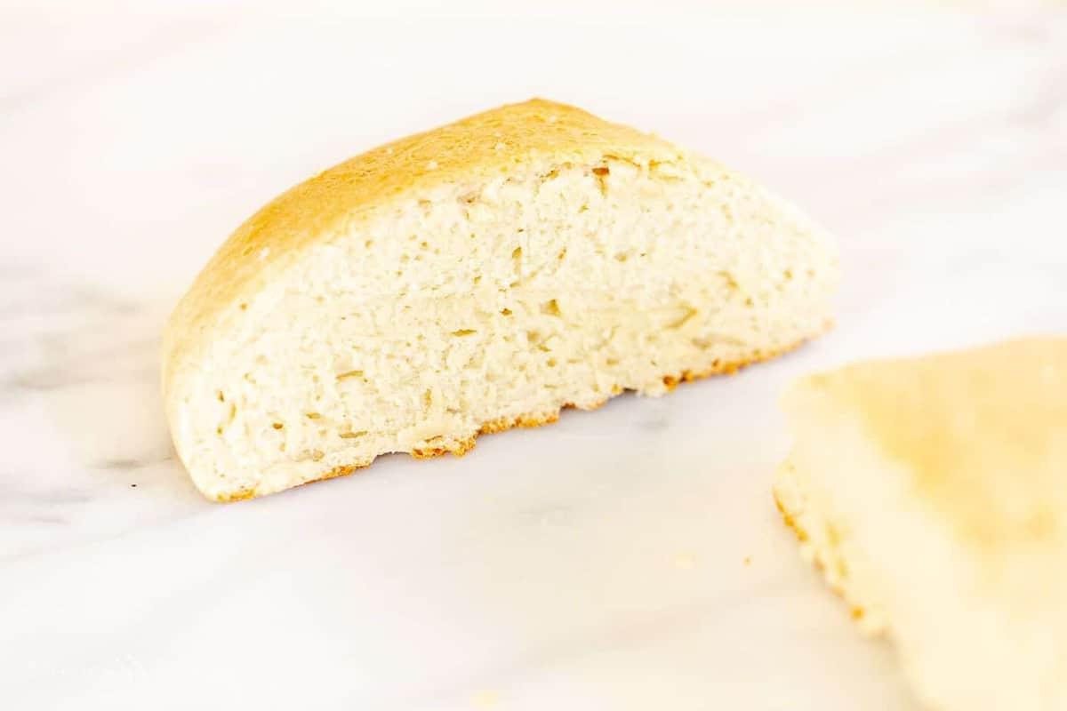 Hausgemachtes Brot im Dutch Oven 3 Eine Marmoroberfläche mit einem halbierten Laib hausgemachtem Rosmarinbrot.