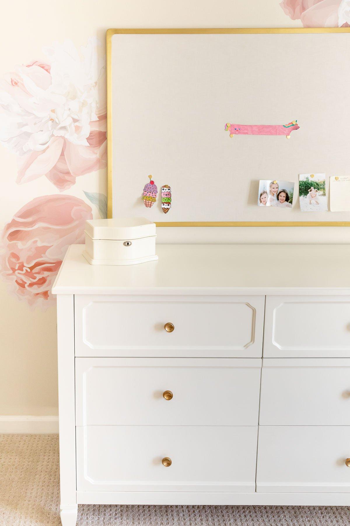 Pottery Barn Kids: Der Look zum kleinen Preis 3 Eine weiße Kommode mit sorgfältig arrangierten Blumen, die den charmanten Stil von Pottery Barn Kids widerspiegelt und zeigt, wie man diesen Look günstig nachahmen kann.