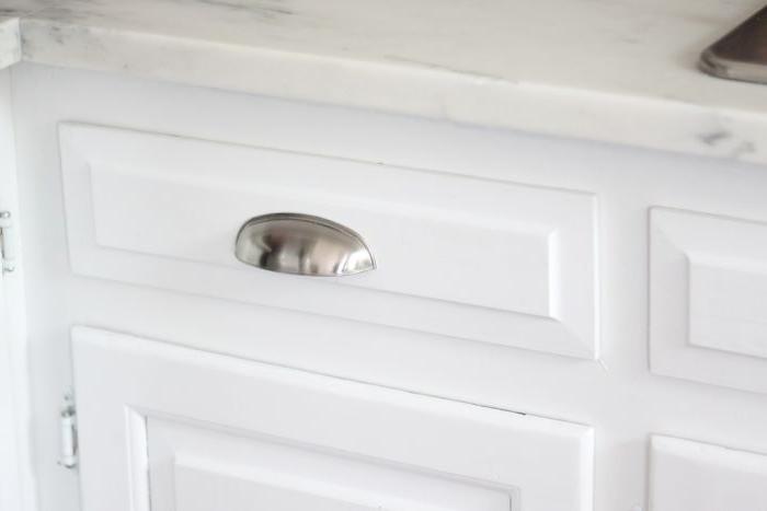 Ein weißer Küchenschrank mit einem silbernen Griff, ideal für Budget-Ideen im Bauernhausstil.