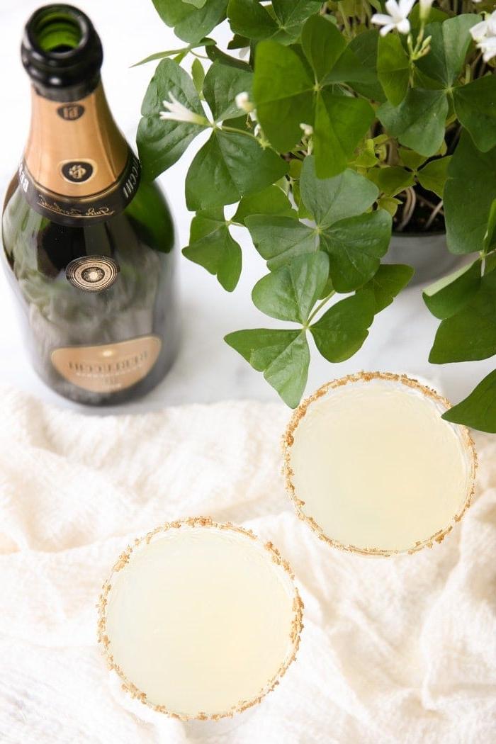 Shot of Gold: Ihr eleganter Sekt-Limonaden Cocktail für festliche Anlässe Zwei goldene St. Patrick's Day Cocktails neben einer Flasche Champagner