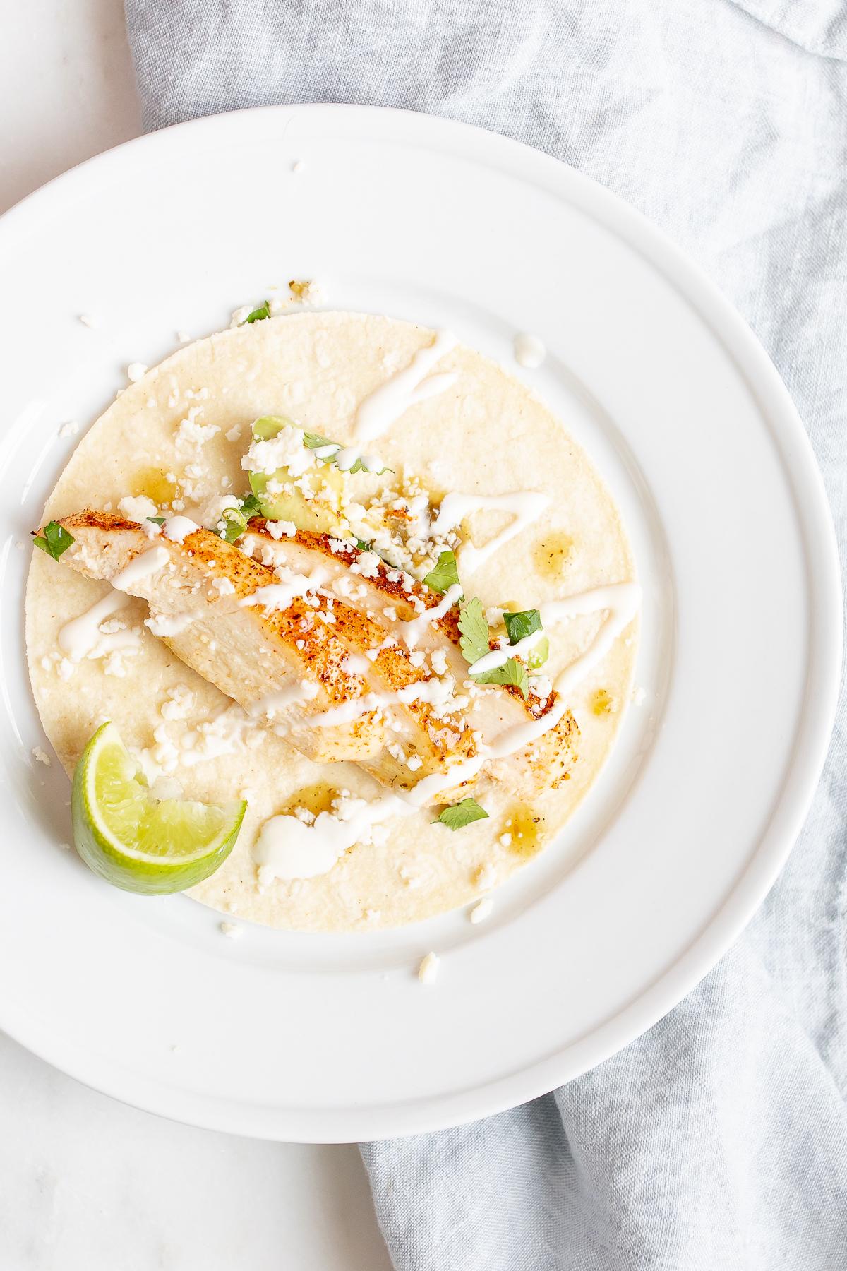 Weiche Hähnchen-Tacos 3 Hähnchen-Soft-Tacos in Mais-Tortillas auf einer weißen Oberfläche.
