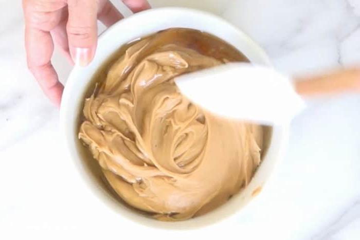 Erdnussbutter und Honig werden in einer weißen Rührschüssel vermischt.