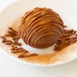 Mexikanische Heiße Schokoladenbomben 21 Mexikanischer Trinkschokolade Bombe auf einem weißen Teller, für die Rezeptkarte.