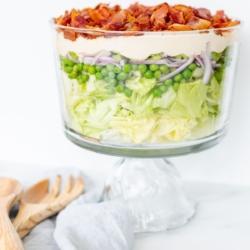 Siebenschichtsalat 21 Sieben-Schicht-Salat mit Speck belegt auf einer Marmorarbeitsplatte