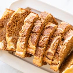 Ein ganzer Laib Kürbis-Käsekuchen-Brot auf einer weißen Platte, bereit zum Servieren.