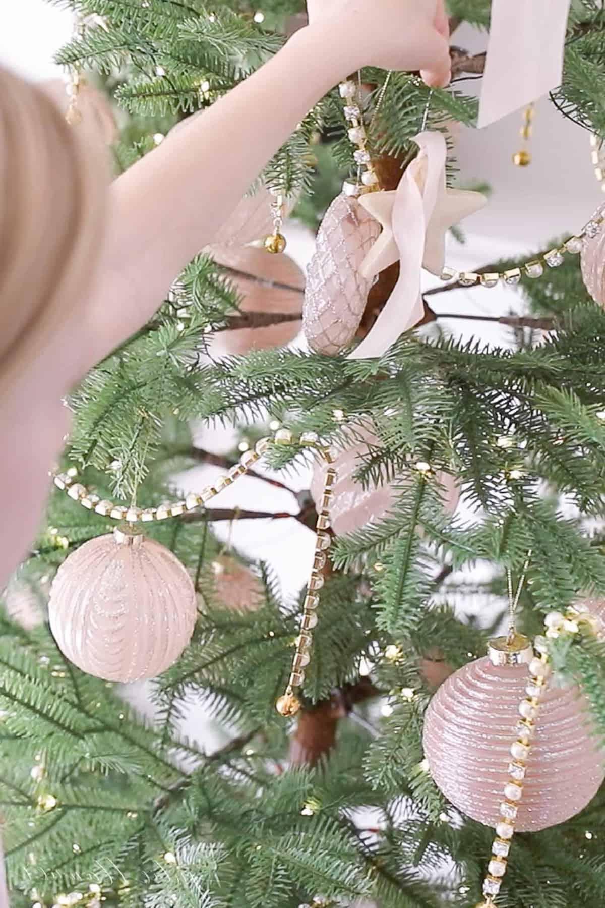 Die Kante des Gesichts und der Hände eines kleinen Mädchens, das selbstgemachte Salzteig-Ornamente an einen Weihnachtsbaum hängt.
