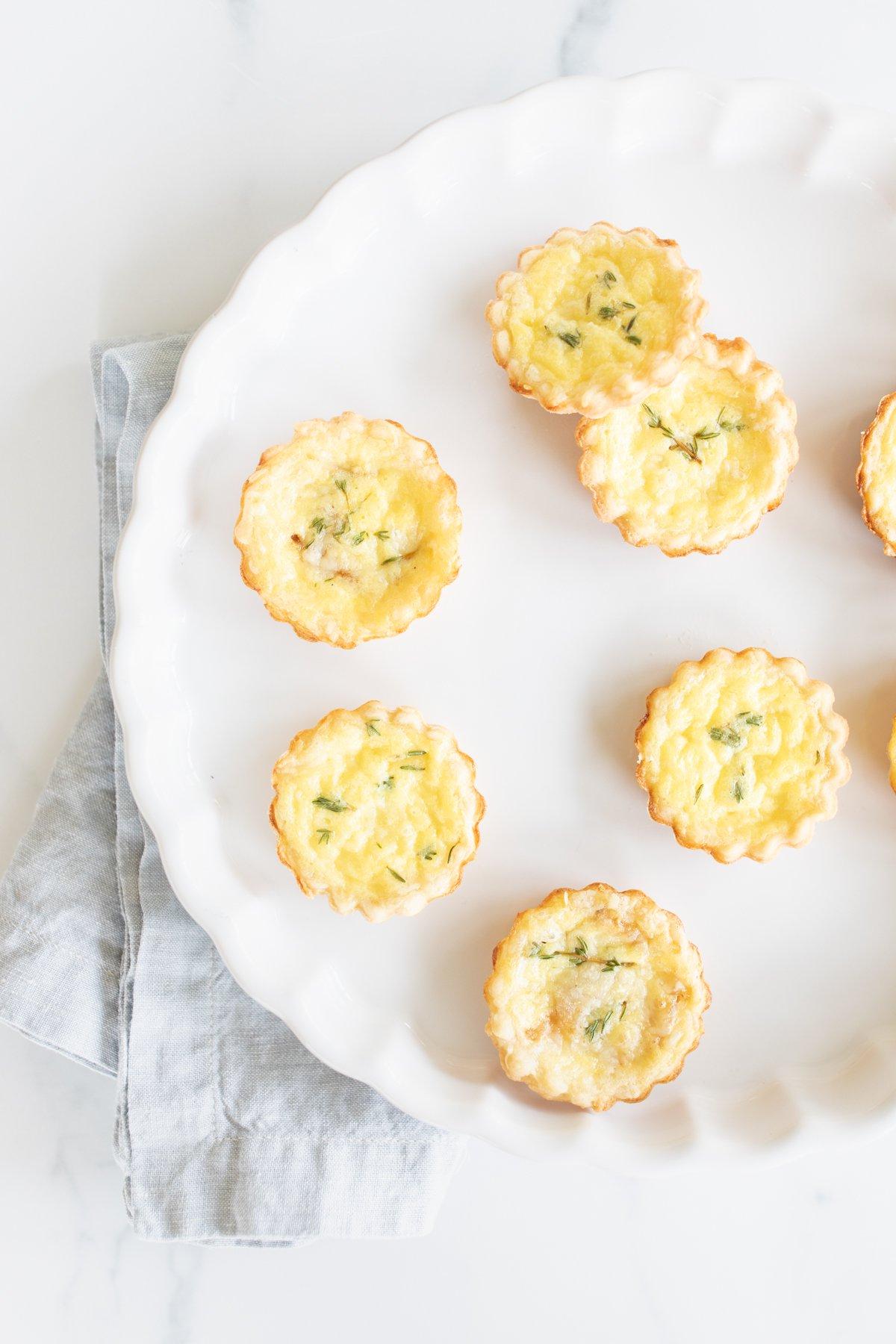 Muttertags-Brunch-Ideen 26 Mini-Käsetörtchen auf einer weißen Platte.