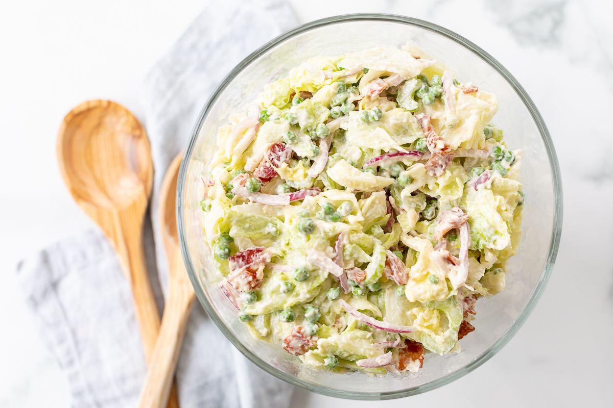 Siebenschichtsalat 4 Ein Sieben-Schicht-Salat, in einer Glasschale angerichtet, mit Holzlöffeln daneben