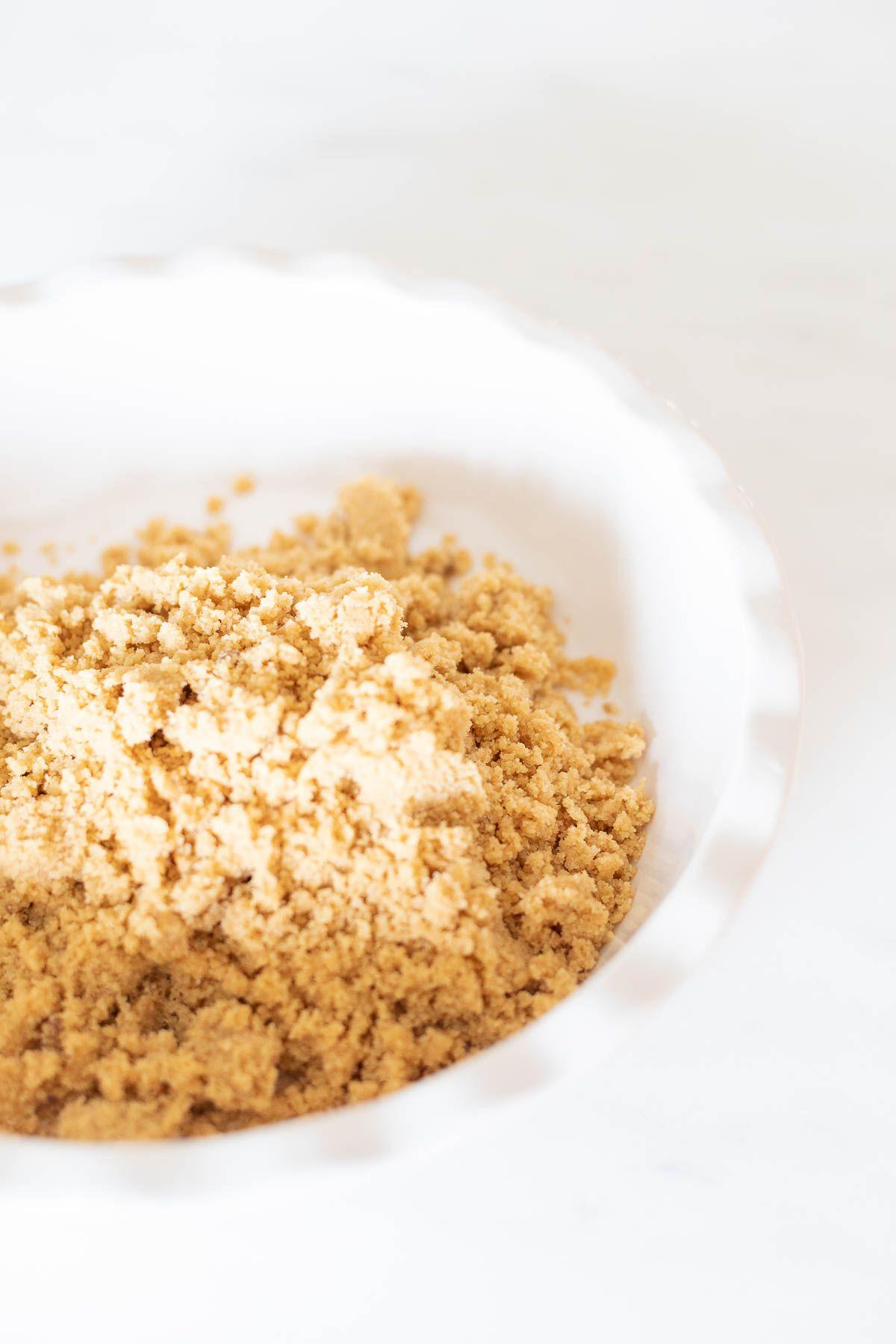 Mürbeteigboden ohne Backen Rezept 3 Zutaten für einen No-Bake Shortbread-Kuchenboden in einer weißen, geriffelten Keramik-Kuchenform