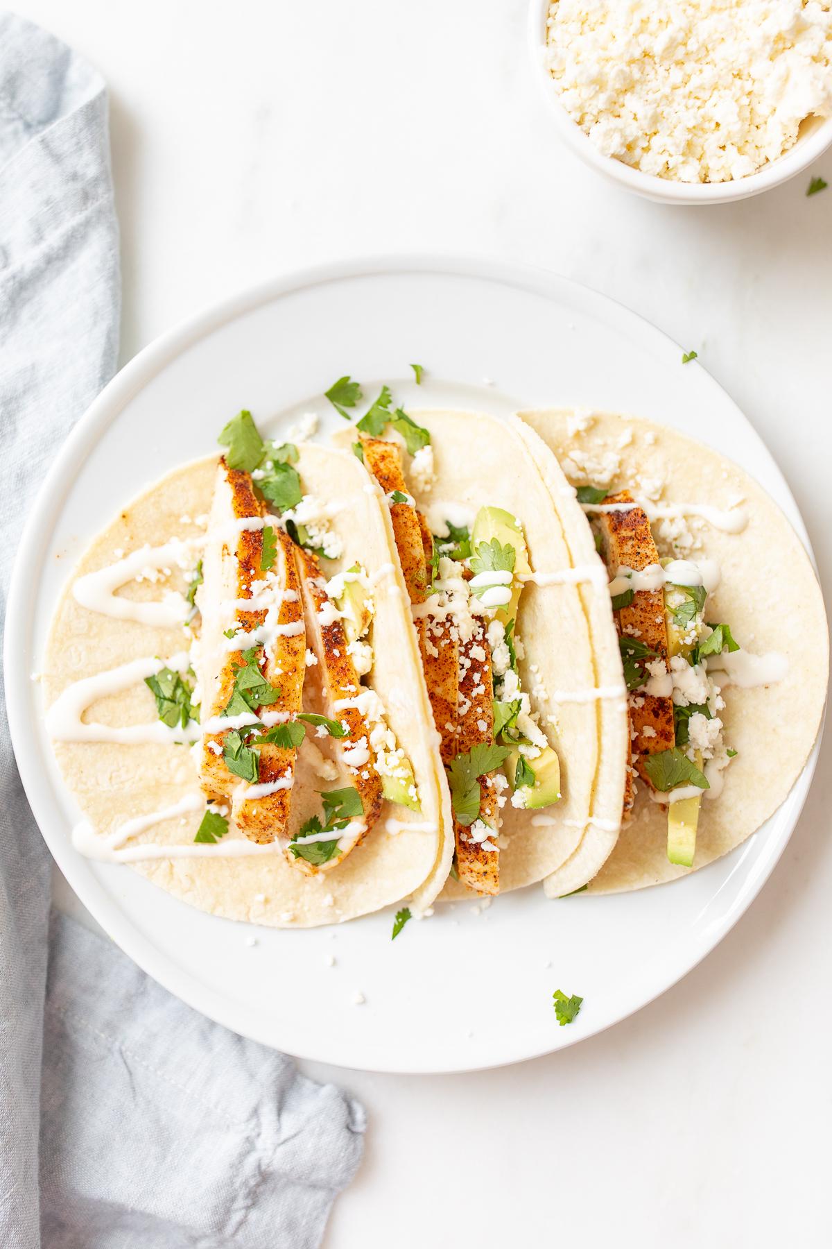 Weiche Hähnchen-Tacos 4 Hähnchen-Tacos in Mais-Tortillas auf einer weißen Oberfläche.